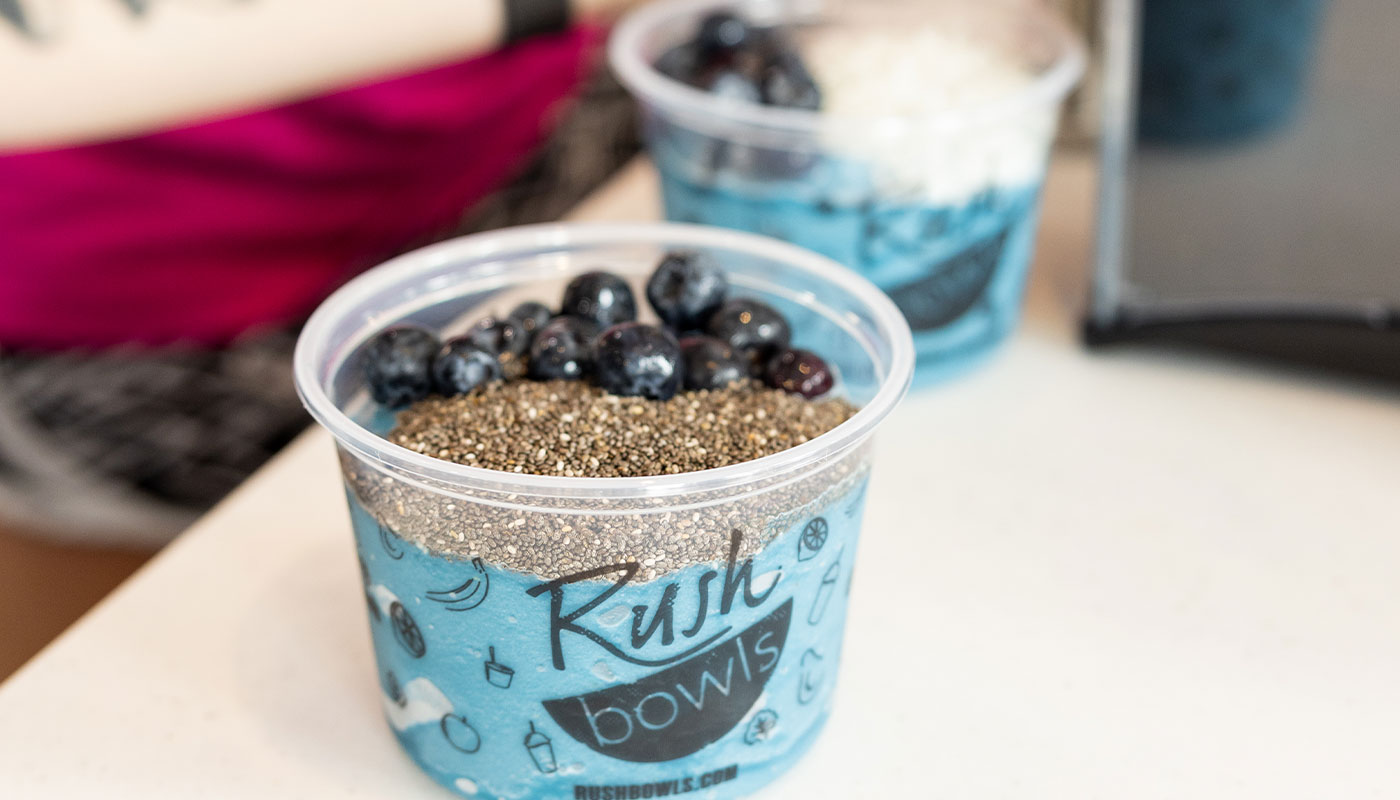 A Rush Bowls owner working and ready to help customers - learn how to start a health food franchise!