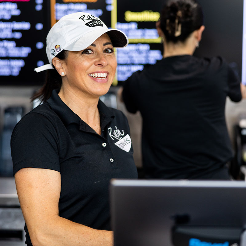 A Rush Bowls owner working and ready to help customers - learn how to start a health food franchise!