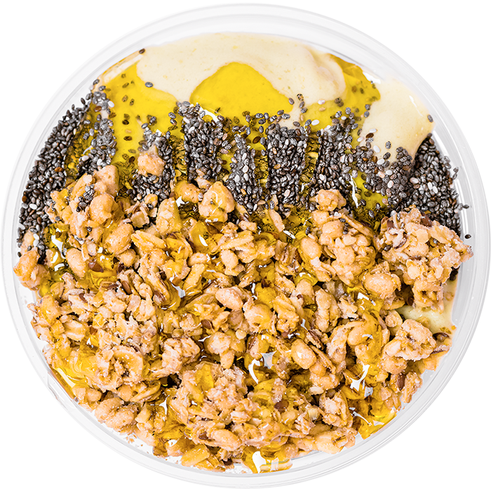 Honey, chai seeds, and granola on top of a matcha smoothie bowl. 
